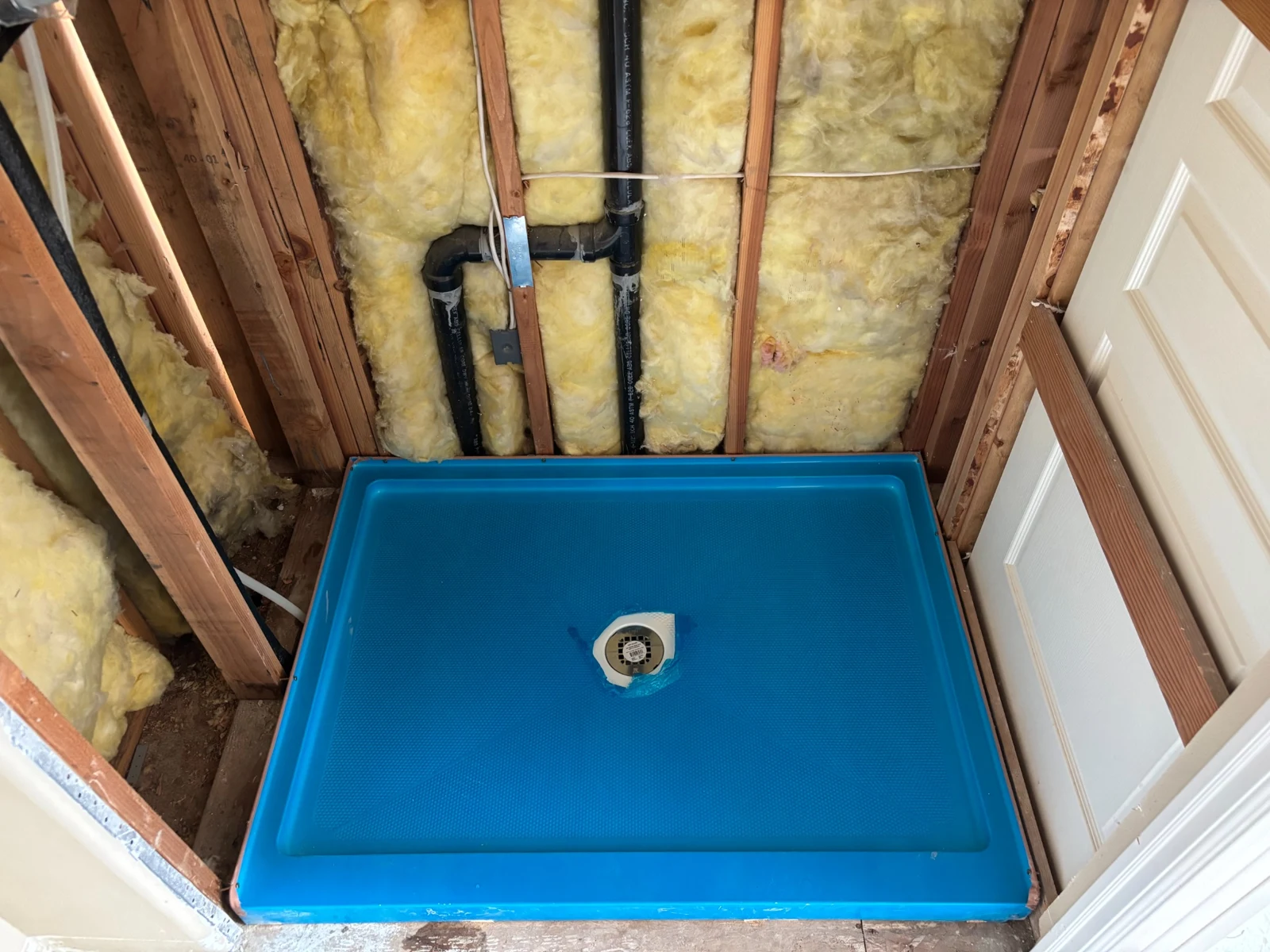Shower base and exposed drain and vent piping during a bathroom remodel