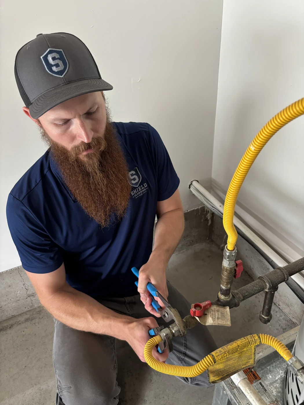 Will Mortensen working on plumbing connections beside a residential water heater