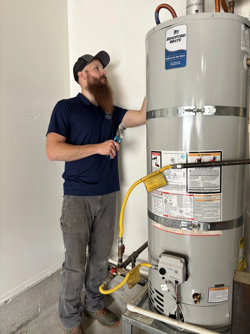 Will Mortensen beside a Bradford White tank water heater during installation work